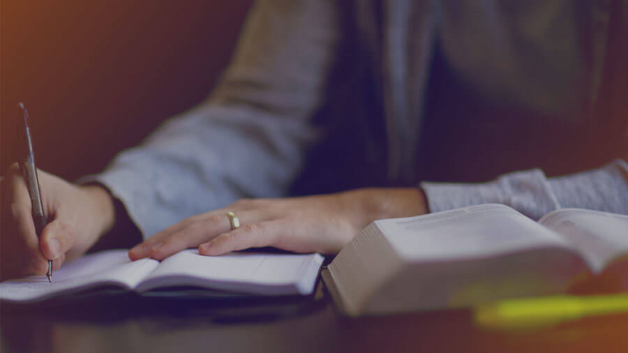 A person writing in a journal while reading a Bible at Pinelake Church.