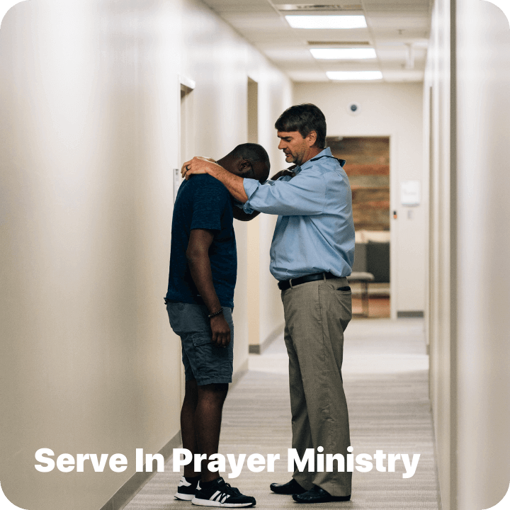 Two men standing and praying at Pinelake Church